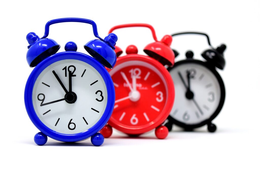 three alarm clocks - one red, one blue and one black